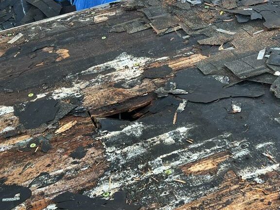 Decking damage on a roof from water penetrating the asphalt shingle.